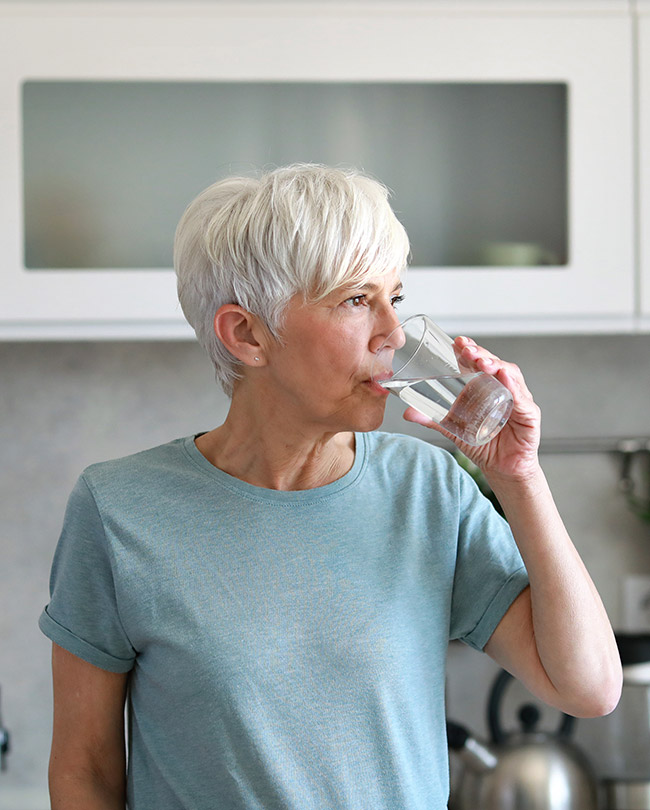 Frau trinkt Wasser aus einem Glas
