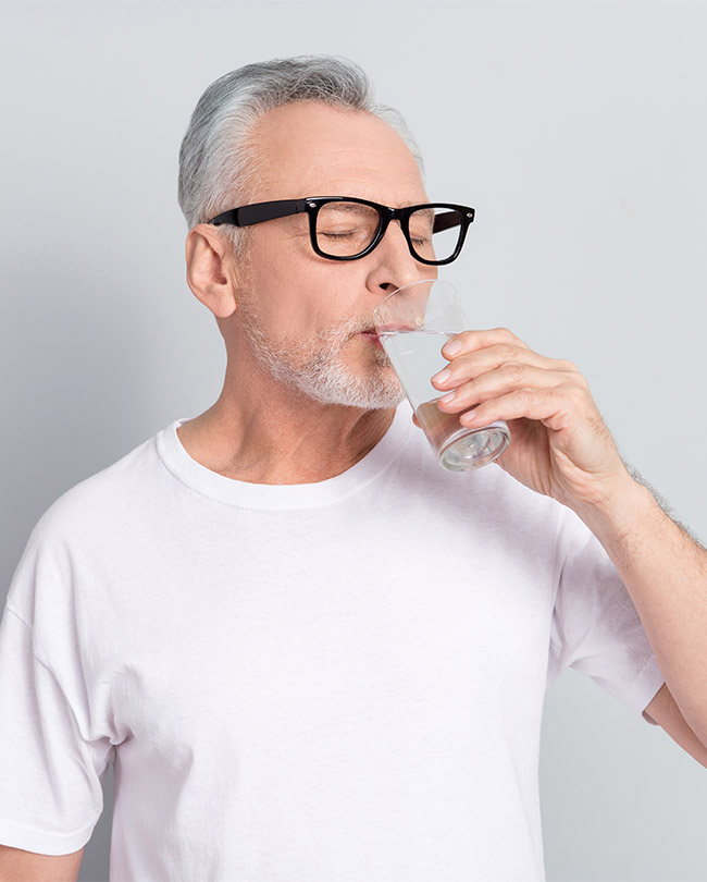 Mann trinkt Wasser aus einem Glas